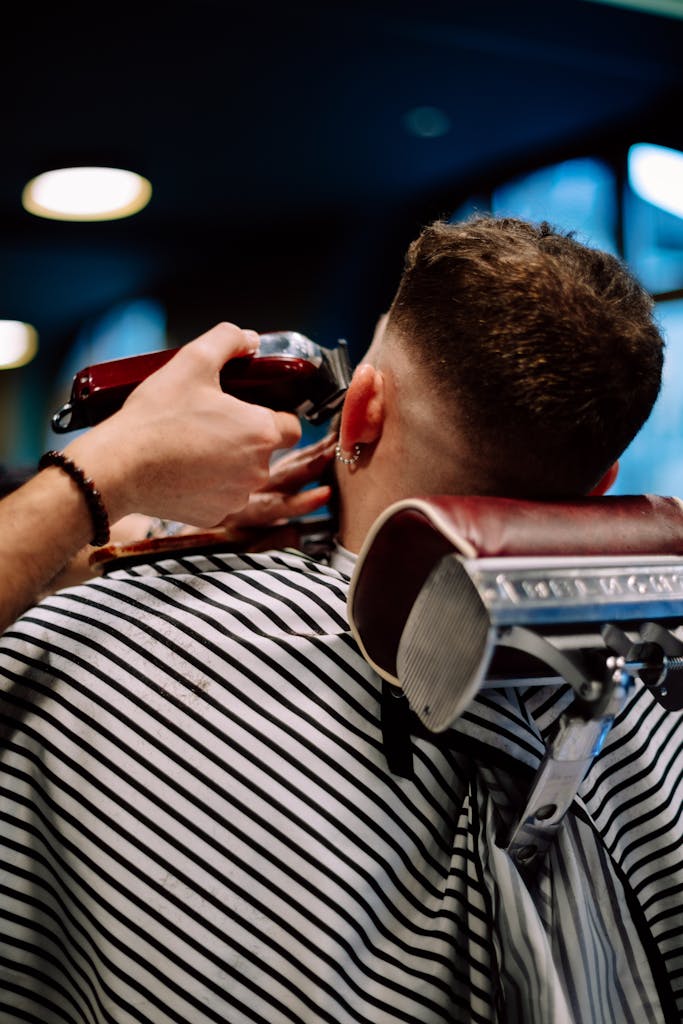 A barber skillfully trims a man's hair at a Geneva barber shop, showcasing precision and style.